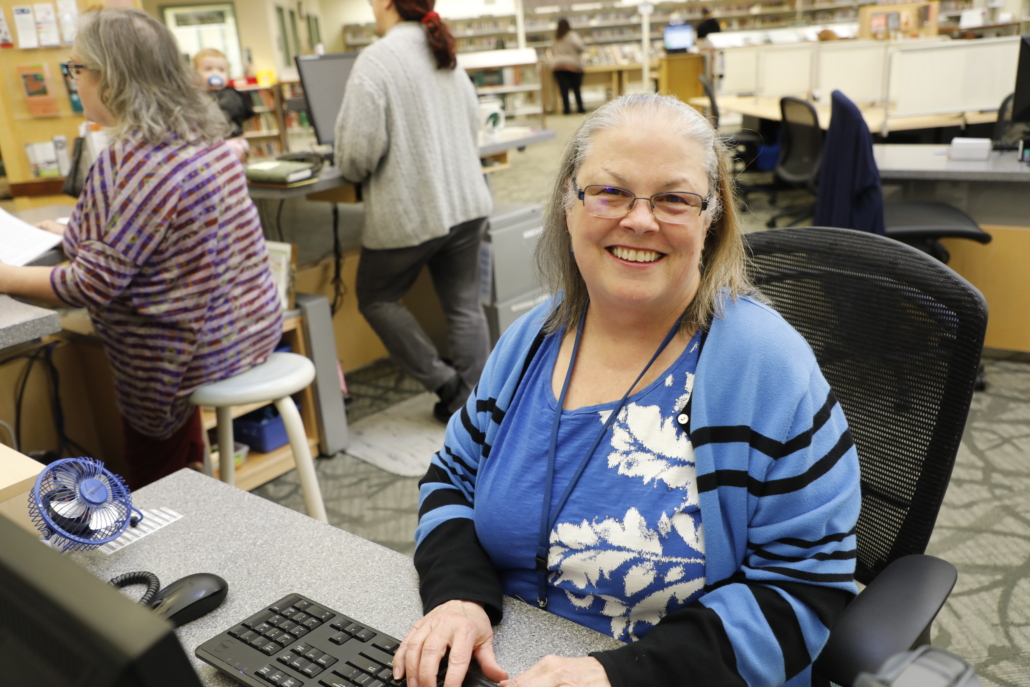 Friendly librarian helping person request a book through Interlibrary Loan