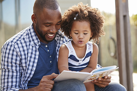 Father and child enjoy a book together (Links to information about the impact of Pierce County Library Foundation donations)