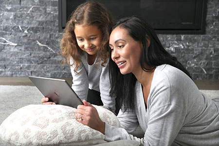 Caregiver and child enjoying e-books in front of the fire (Links to OverDrive for e-books, e-audibooks, digital magazines and videos)