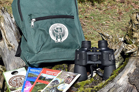 Green Check Out Washington backpack with binoculars and state park information (Links to Check Out Washington information)