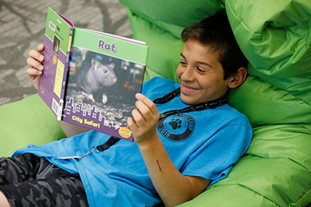 Tween reads a book on a beanbag chair