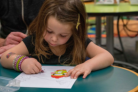 A child colors a coloring page at the library